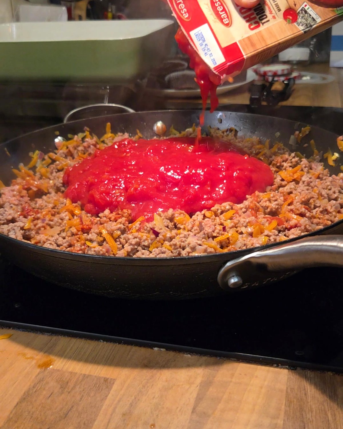 Krossade tomater hälls ner i köttfärsen